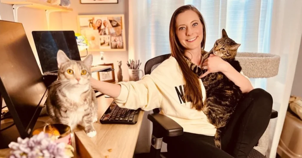 Girl sitting with two cats at desk