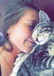 Girl snuggling with kitten that had Feline Infectious Peritonitis