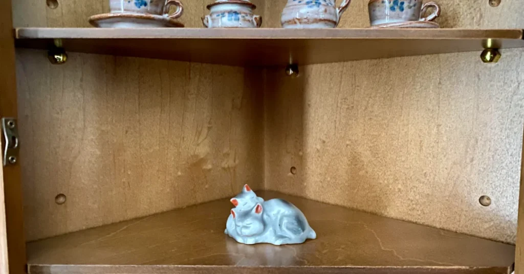 Little cat figurine inside wooden curio cabinet